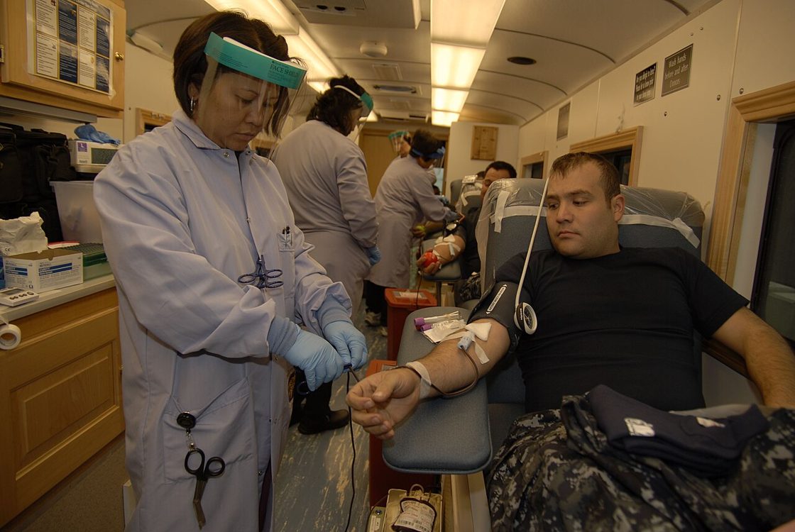 A phlebotomist draws blood from a patient in a mobile clinic